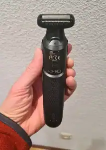 Afeitadora eléctrica Braun en mano, diseño ergonómico y negro.