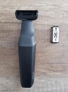Afeitadora eléctrica Philips y batería en superficie de madera.